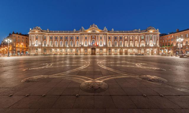 La place du Capitole à Toulouse, à la tombée de la nuit avec, au sol, la croix occitane dessinée par Raymond Moretti.