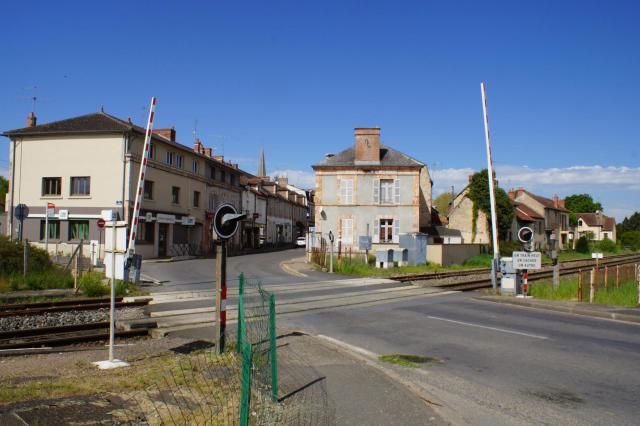 Passage à niveau à proximité de la gare qui se trouve à gauche.