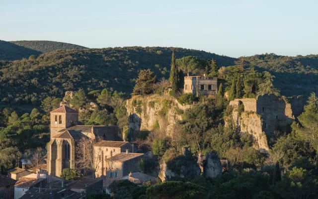 L'église Sainte-Marie (XIIe siècle) et le Roc Castel, un rocher monumental où siègent les ruines du château. Le Cirque de Mourèze est un cirque ruiniforme dolomitique dont l’aspect chaotique est issue de l'érosion d’une roche sédimentaire appelée dolomie. Mourèze, Hérault, France.