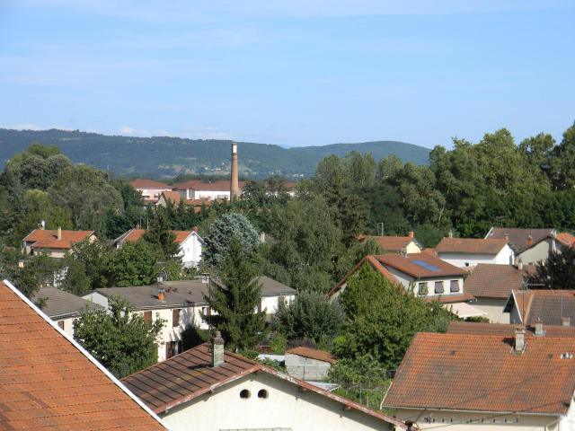 Vue sur Pont-de-Chéruy depuis les hauteurs ; au loin, une cheminée de l'ancienne usine de la société Grammont.