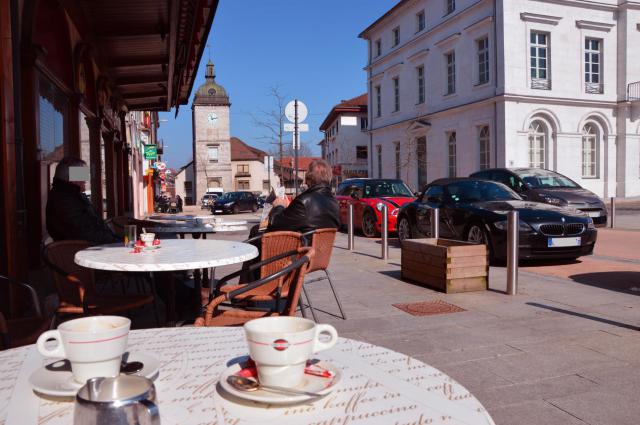 Champagnole centre-ville, Jura, Franche-Comté. Terrasse de café sur le trottoir de l´Avenue de la République avec le château d'eau de…