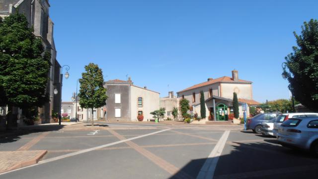 Place de l'église de Botz-en-Mauges, avec l'église sur la gauche et le bâtiment de la mairie-bureau de poste sur la droite.