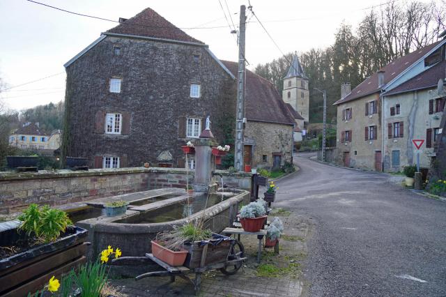 Le centre du bourg de Gouhenans avec l'église et une fontaine.