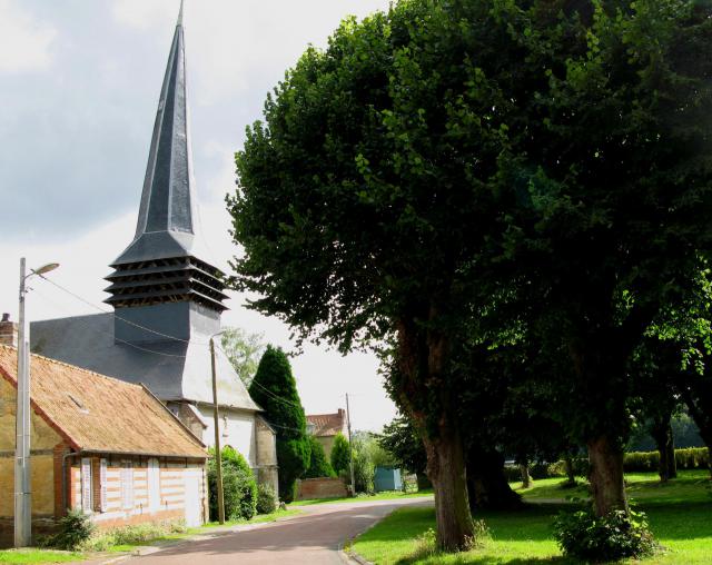 Quevauvillers (Somme, France) - L'église et la place vues en venant du château. La flèche du clocher est légèrement tordue. .
