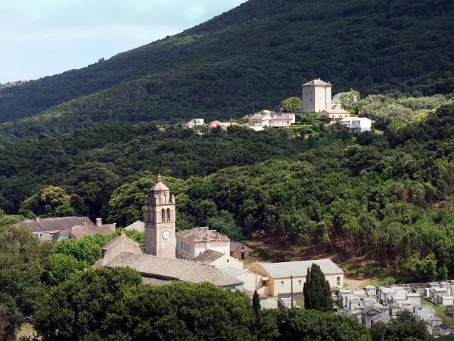 Luri (Corse) - Piazza dont on voit le clocher de l'église SS. Pietro e Paolo et le cimetière. Au fond, Castiglione