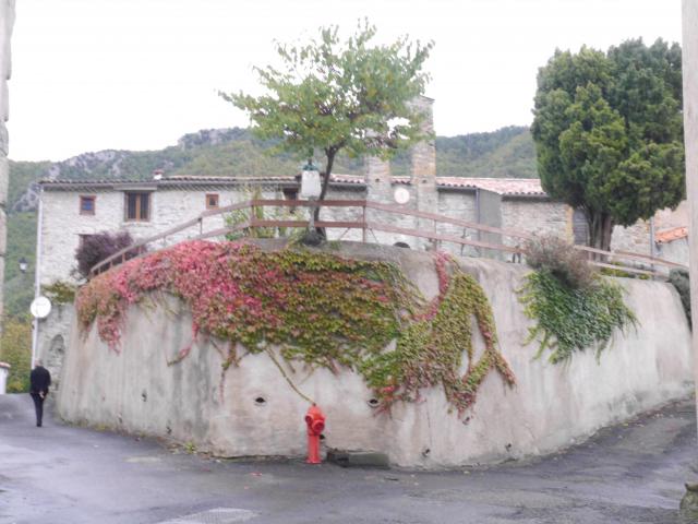 Mur de l'église de cailla dont le presbytère a été transformé en logements, on peut voir le clocher en fond