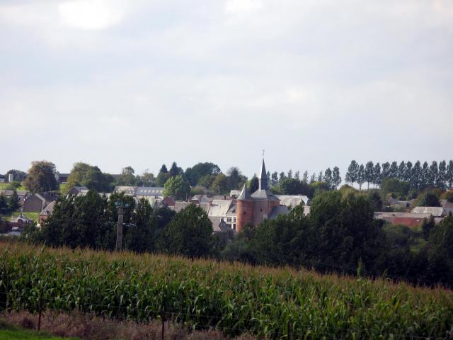 Plomion (Aisne, France) - Le village dans son cadre verdoyant et avec son église fortifiée. Vue depuis la route venant de Bancigny. Lieu…